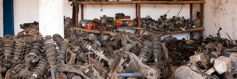 Regale und Stapel mit gebrauchten Fahrzeugteilen in einem Lagerraum