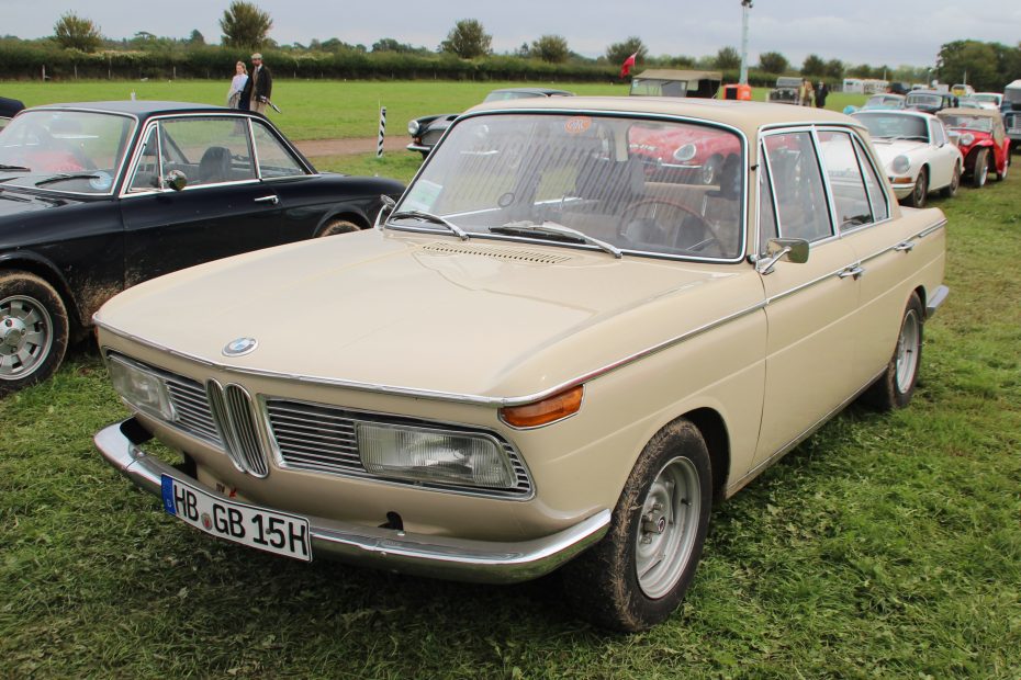 Cremefarbene BMW-Limousine der Neuen Klasse auf einer Wiese