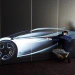 Zwei Designer prüfen die mit Klebeband gezeichnete Seitenansicht eines Konzeptfahrzeugs an der Wand